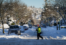 A Canada Post letter carrier crosses a snow and ice covered road while delivering mail in Burnaby, B.C., on Wednesday, December 21, 2022. Photo by: The Canadian Press/Darryl Dyck