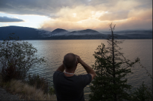 Wildfire evacuee Rob Lessard watches from across Okanagan Lake, trying to see whether the White Rock Lake wildfire has burned his home or not. Photo by Jesse Winter / Canada's National Observer