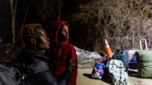 Pamela Haiala, originally from Congo, looks towards Canada with her son as they wait to cross into Canada at Roxham Road, an illegal crossing point from New York State to Quebec, in Champlain, N.Y., on March 24, 2023. (Carlos Osorio/Reuters)