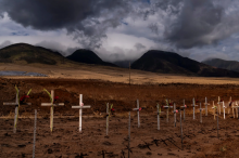 A row of crosses in a brown field in front of mountains and dark clouds - Jae C. Hong/Associated Press