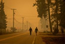 Two men walk along a road in Scotch Creek, B.C., as wildfire smoke fills the air on Aug. 19, 2023. (Ben Nelms/CBC)