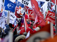 A young child riding on her parents' shoulders is lost in a sea of flags during a huge union protest against the CAQ government in Montreal on Saturday, Nov. 29, 2025. Photo by Allen McInnis /Montreal Gazette