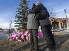 A couple embraces in front of a memorial honouring the victims of a mass shooting in Tumbler Ridge, BC, on Feb. 12, 2026. Photo by Christinne Muschi, the Canadian Press.