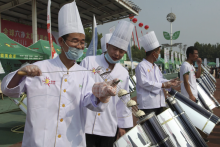 Chefs prepare to cook buns in a solar cooker that using a metal and glass vacuum tube heated by mirrors curved to capture the sun's heat in Dezhou in the eastern Shandong province in China. This is just one clean energy innovation helping China to reduce its carbon emissions. Photo by: Fu Ting/AP